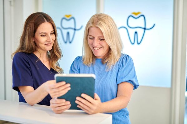 Praxismanagerin Cigdem erklärt einer Patientin am Empfang der Zahnarztpraxis Bodensee Dental - Dr. Kronauer & Kollegen in Lindau den Anamnesebogen am Tablet.