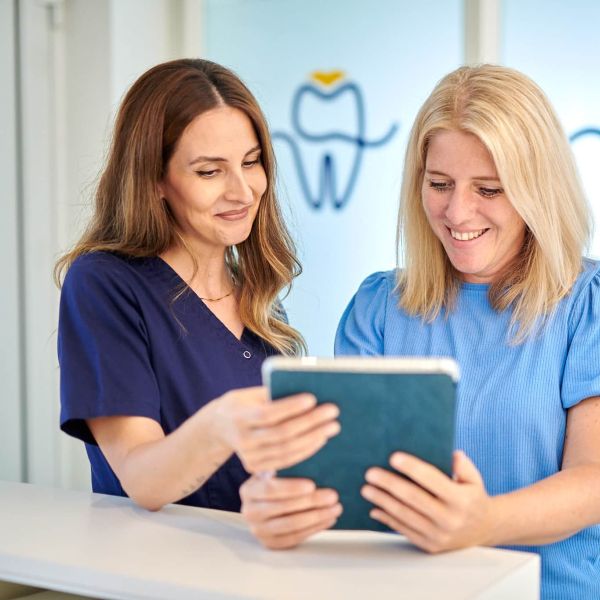 Praxismanagerin Cigdem erklärt einer Patientin am Empfang der Zahnarztpraxis Bodensee Dental - Dr. Kronauer & Kollegen in Lindau den Anamnesebogen am Tablet.
