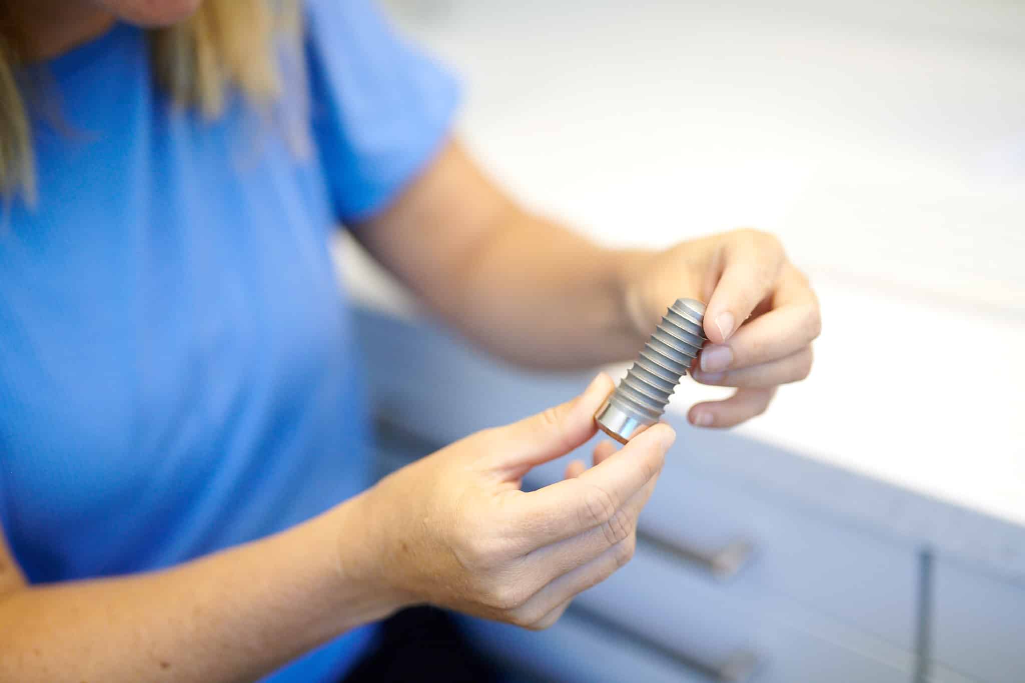 Eine Patientin sitzt im Labor und schaut sich ein Implantat an.